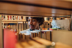 Student working in library sorting books.
